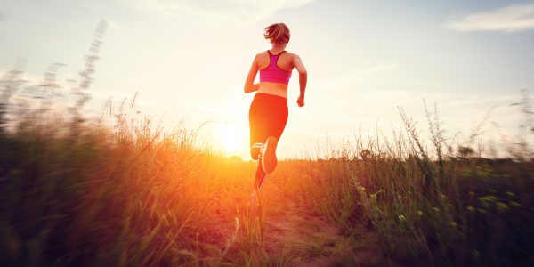 Young woman running on a rural road at sunset Young woman running on a rural road at sunset in summer forest. Lifestyle sports background